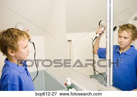 Boy blow-drying hair at bathroom mirror View Large Photo Image Stock Photo - Boy blow-drying hair at bathroom mirror. Fotosearch