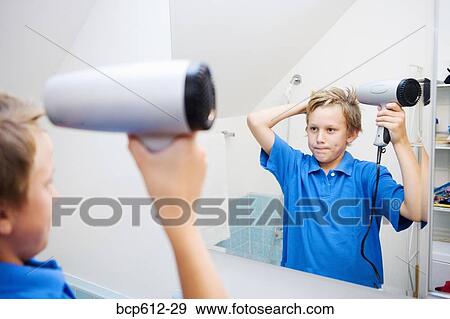 Boy blow-drying hair in bathroom mirror View Large Photo Image Stock Photo - Boy blow-drying hair in bathroom mirror. Fotosearch