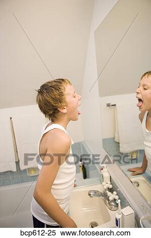 Boy looking at tongue in bathroom mirror View Large Photo Image Stock Photography - Boy looking at tongue in bathroom mirror. Fotosearch