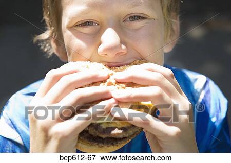 Closeup of boy eating hamburger View Large Photo Image Stock Photo - Closeup of boy eating hamburger. Fotosearch