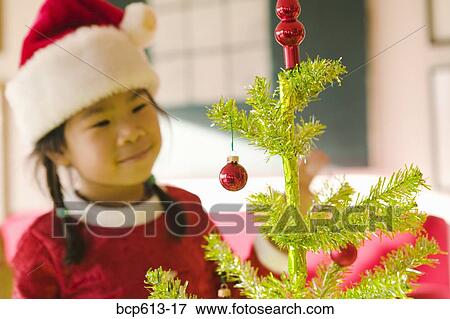Stock Photo - Closeup of girl looking at Christmas tree. Fotosearch