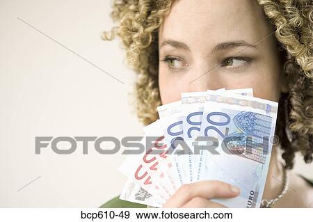 Closeup of woman hiding face behind Euros View Large Photo Image Stock Photo - Closeup of woman hiding face behind Euros. Fotosearch