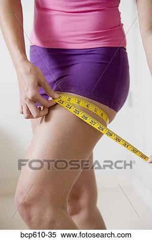 Closeup of woman measuring her thigh View Large Photo Image Stock Photography - Closeup of woman measuring her thigh. Fotosearch