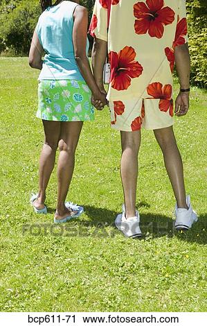 Couple holding hands on sunny lawn View Large Photo Image Stock Image - Couple holding hands on sunny lawn. Fotosearch
