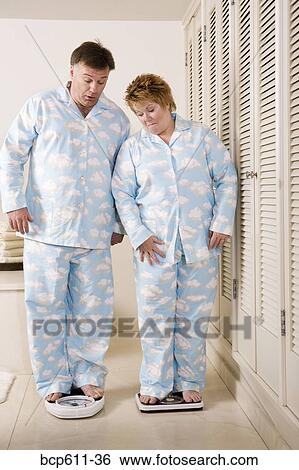 Couple standing on bathroom scales View Large Photo Image Stock Photograph - Couple standing on bathroom scales. Fotosearch