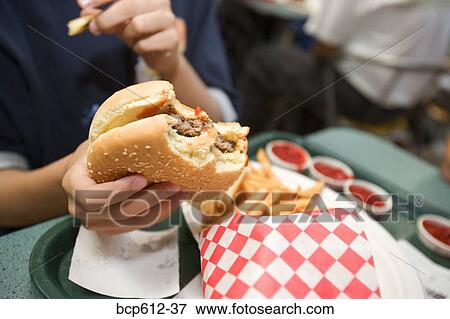 Stock Photo - French fries and burger in boy's hand. Fotosearch
