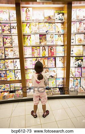 Girl looking at magazine display View Large Photo Image Stock Image - Girl looking at magazine display. Fotosearch