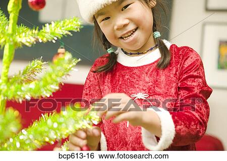 Happy girl decorating Christmas tree View Large Photo Image Stock Photograph - Happy girl decorating Christmas tree. Fotosearch
