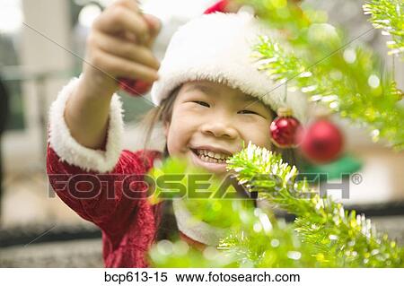 Happy girl decorating Christmas tree View Large Photo Image Stock Photography - Happy girl decorating Christmas tree. Fotosearch