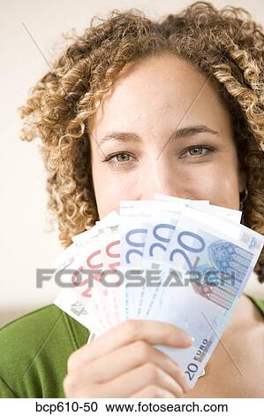 Stock Image - Happy woman hiding behind Euros. Fotosearch