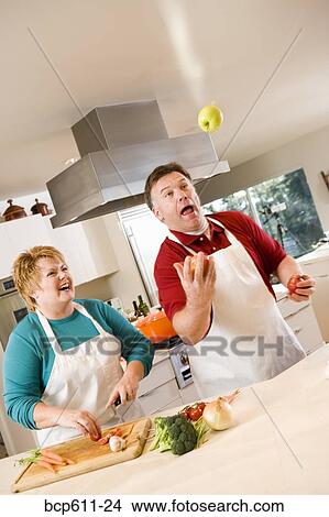 Husband juggling fruit with laughing wife View Large Photo Image Picture - Husband juggling fruit with laughing wife. Fotosearch