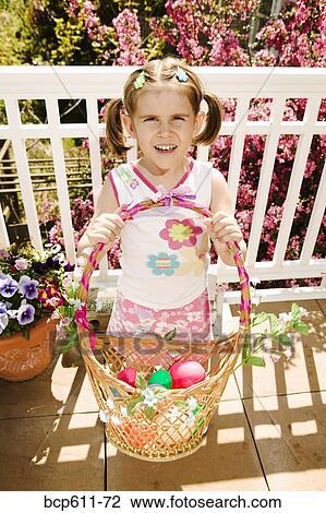 Stock Image - Little girl with Easter basket on porch. Fotosearch
