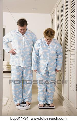 Overweight couple on bathroom scales View Large Photo Image Picture - Overweight couple on bathroom scales. Fotosearch