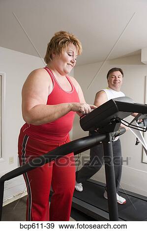 Overweight couple using exercise machines View Large Photo Image Stock Photo - Overweight couple using exercise machines. Fotosearch