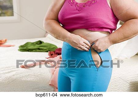 Overweight woman squeezing into small pants View Large Photo Image Picture - Overweight woman squeezing into small pants. Fotosearch