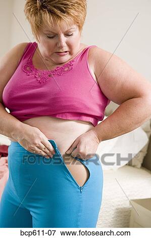 Overweight woman squeezing into small pants View Large Photo Image Stock Photo - Overweight woman squeezing into small pants. Fotosearch