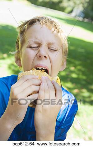 Portrait of boy eating hamburger outside View Large Photo Image Picture - Portrait of boy eating hamburger outside. Fotosearch