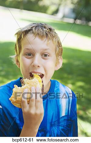 Portrait of boy eating hamburger outside View Large Photo Image Stock Image - Portrait of boy eating hamburger outside. Fotosearch