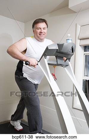 Stock Photo - Portrait of overweight man on treadmill. Fotosearch