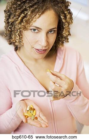 Stock Photography - Portrait of woman with handful of pills. Fotosearch