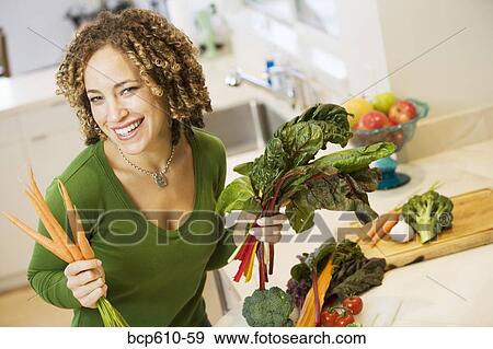 Portrait of woman with vegetables in kitchen View Large Photo Image Stock Photo - Portrait of woman with vegetables in kitchen. Fotosearch
