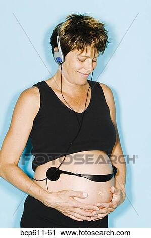 Pregnant woman with headphones on belly View Large Photo Image Stock Image - Pregnant woman with headphones on belly. Fotosearch