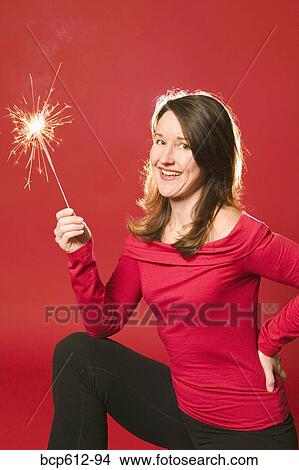 Smiling woman holding burning sparkler View Large Photo Image Picture - Smiling woman holding burning sparkler. Fotosearch