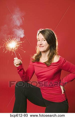 Smiling woman holding burning sparkler View Large Photo Image Stock Image - Smiling woman holding burning sparkler. Fotosearch