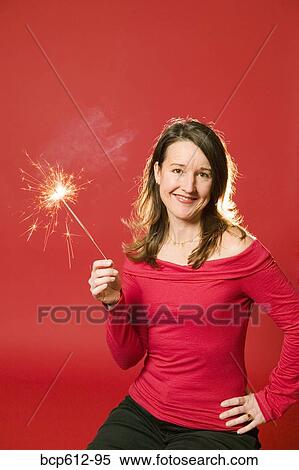 Stock Photography - Smiling woman holding burning sparkler. Fotosearch