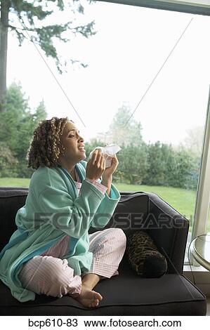 Sneezing woman on couch in pajamas View Large Photo Image Stock Image - Sneezing woman on couch in pajamas. Fotosearch