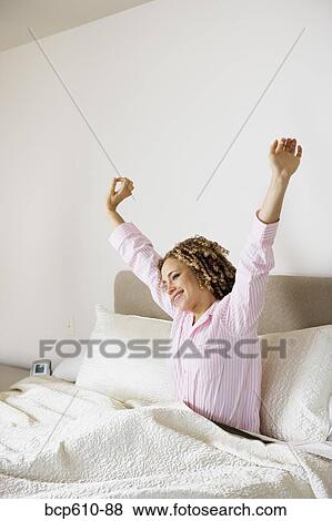 Stock Photo - Woman awaking and stretching in bed. Fotosearch