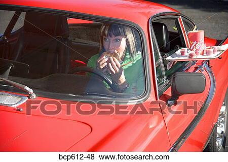 Woman eagerly eating sandwich at drive-in View Large Photo Image Stock Photo - Woman eagerly eating sandwich at drive-in. Fotosearch