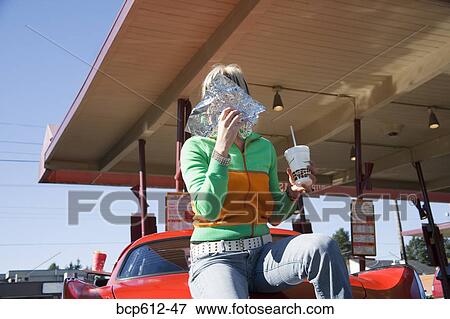 Stock Photo - Woman eating at drive-in restaurant. Fotosearch