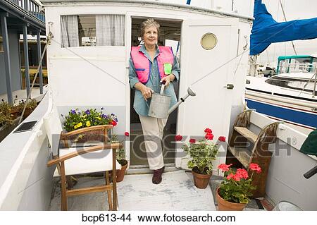 Woman on houseboat watering plants View Large Photo Image Picture - Woman on houseboat watering plants. Fotosearch