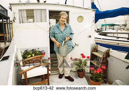 Woman on houseboat watering plants View Large Photo Image Stock Image - Woman on houseboat watering plants. Fotosearch