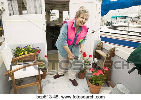 Stock Photography - Woman on houseboat watering plants. Fotosearch