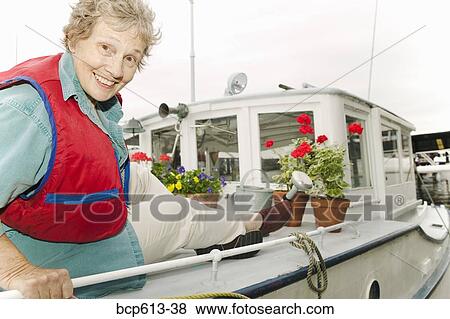 Stock Photo - Woman on houseboat with plants. Fotosearch