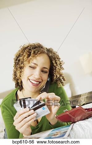 Stock Photograph - Woman on phone with credit cards. Fotosearch
