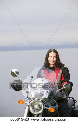Stock Photograph - Woman posing on motorcycle. Fotosearch