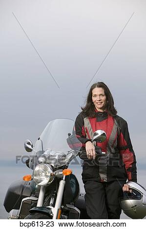 Stock Image - Woman posing with motorcycle. Fotosearch