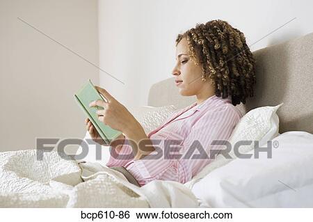 Woman reading book in bed View Large Photo Image Stock Photograph - Woman reading book in bed. Fotosearch