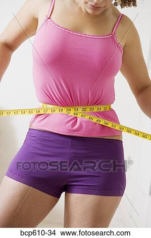Woman squeezing waist with tape measure View Large Photo Image Picture - Woman squeezing waist with tape measure. Fotosearch