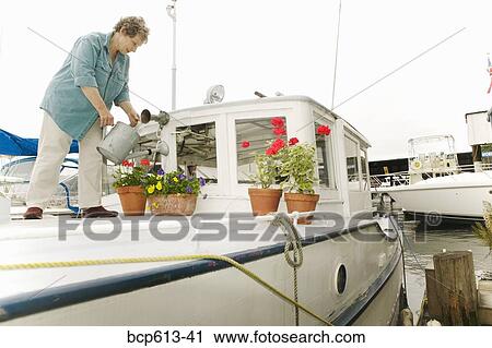 Woman watering plants on houseboat View Large Photo Image Stock Image - Woman watering plants on houseboat. Fotosearch