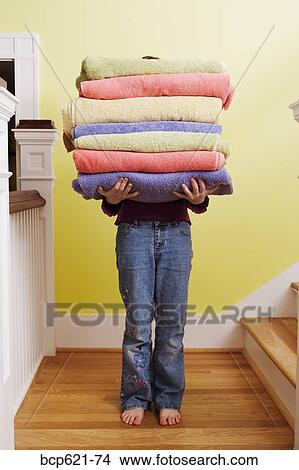 Picture - Child carrying tall stack of towels on stairs. Fotosearch