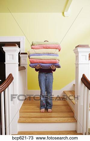 Child carrying tall stack of towels on stairs View Large Photo Image Stock Image - Child carrying tall stack of towels on stairs. Fotosearch