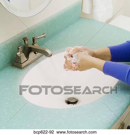 Stock Image - Closeup of washing hands in bathroom sink. Fotosearch
