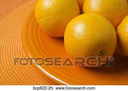 Closeup of whole oranges on orange plate View Large Photo Image Stock Photography - Closeup of whole oranges on orange plate. Fotosearch