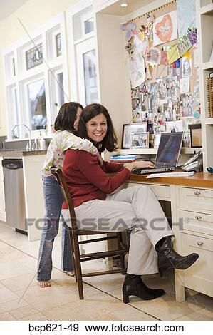 Daughter hugging mom at desk in kitchen View Large Photo Image Stock Photo - Daughter hugging mom at desk in kitchen. Fotosearch