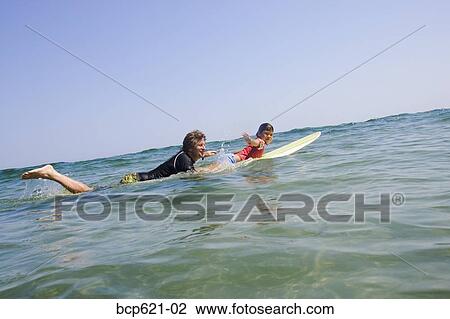 Father and daughter paddling surfboard View Large Photo Image Stock Image - Father and daughter paddling surfboard. Fotosearch