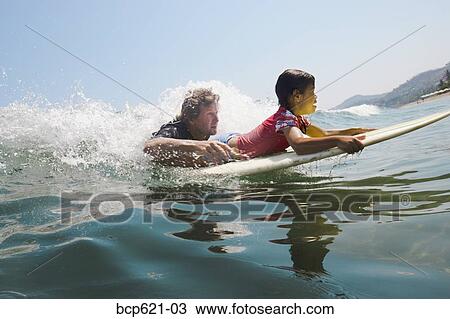 Father and daughter paddling surfboard View Large Photo Image Stock Image - Father and daughter paddling surfboard. Fotosearch